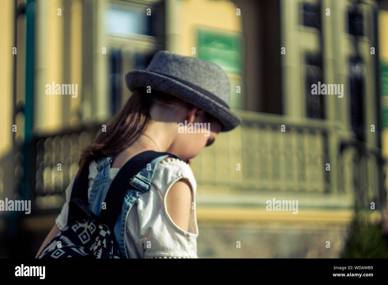 Girl In Sun Hat Looking Down Against Buildings Stock Photo - Alamy