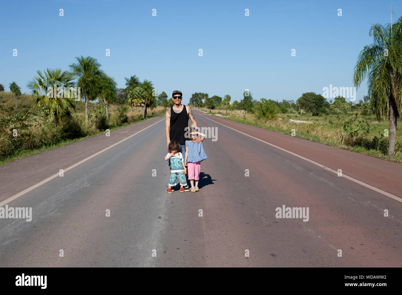 Mid adult man and children standing on rural road in the Pantanal Wetlands, Brazil Stock Photo