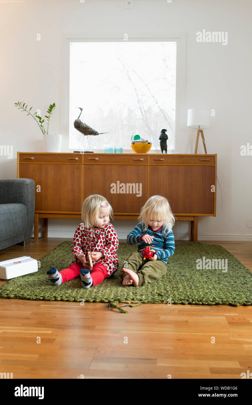 Girls sitting on rug Stock Photo - Alamy