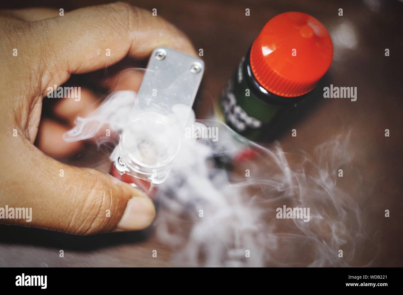 Close-up Of Hand Holding Narcotic Drug With Smoke Emitting From Bottle Stock Photo