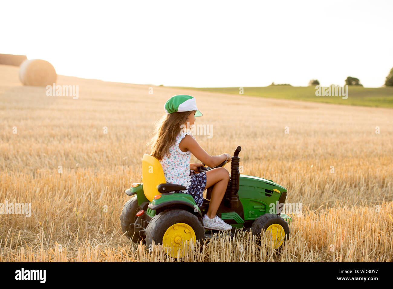 Girl riding toy tractor in field Stock Photo Alamy