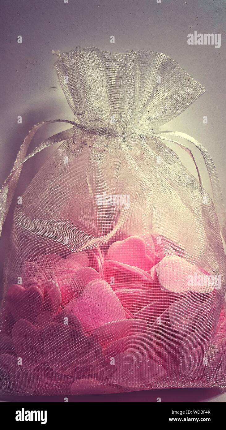 Close-up Of Candy Hearts In Gift Bag Against Wall Stock Photo