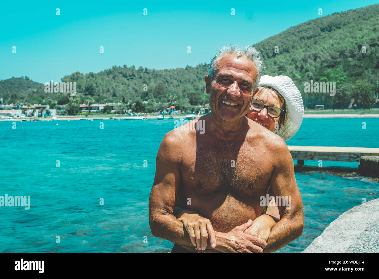 Happy senior couple by the sea enjoying retirement. Elderly couple hugging. Summet time. Stock Photo