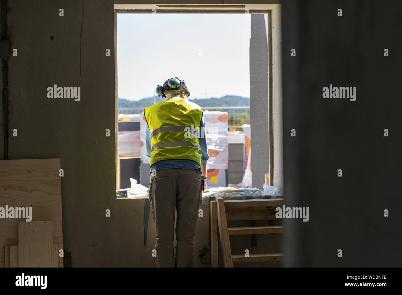 Construction worker by window of incomplete building Stock Photo