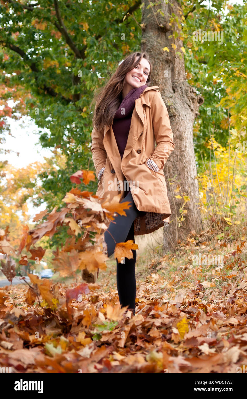 Low Angle View Of Woman Kicking Fallen Autumn Leaves At Park Stock Photo
