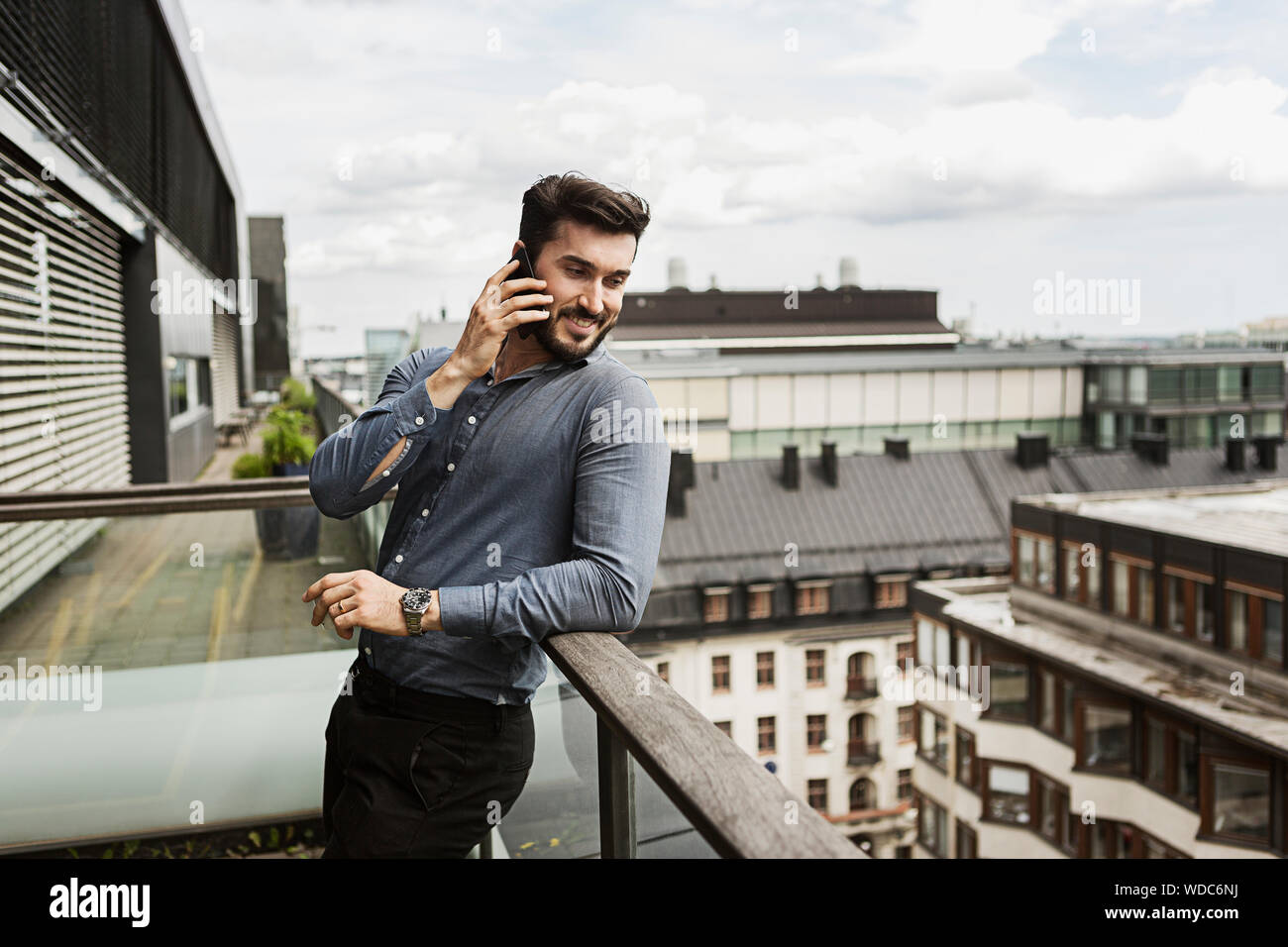 Young man talking on cell phone on balcony Stock Photo