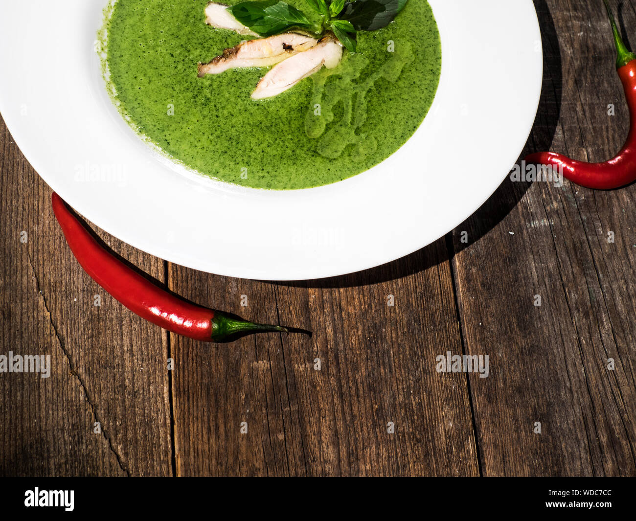 High Angle View Of Spinach Creamy Soup Served In Plate With Red Chilies Stock Photo
