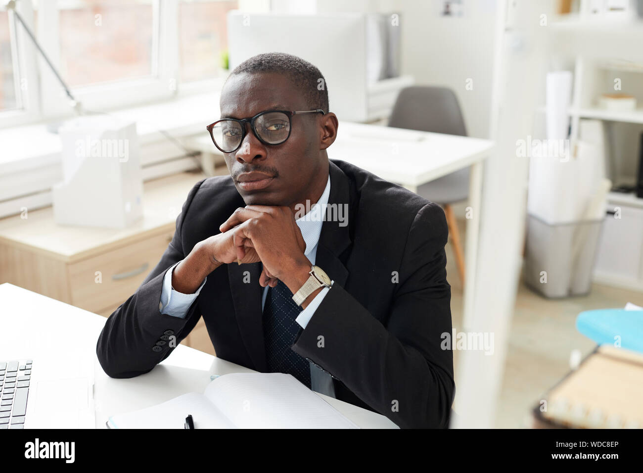 Portrait of African white collar worker in eyeglasses looking at camera while working at the office Stock Photo