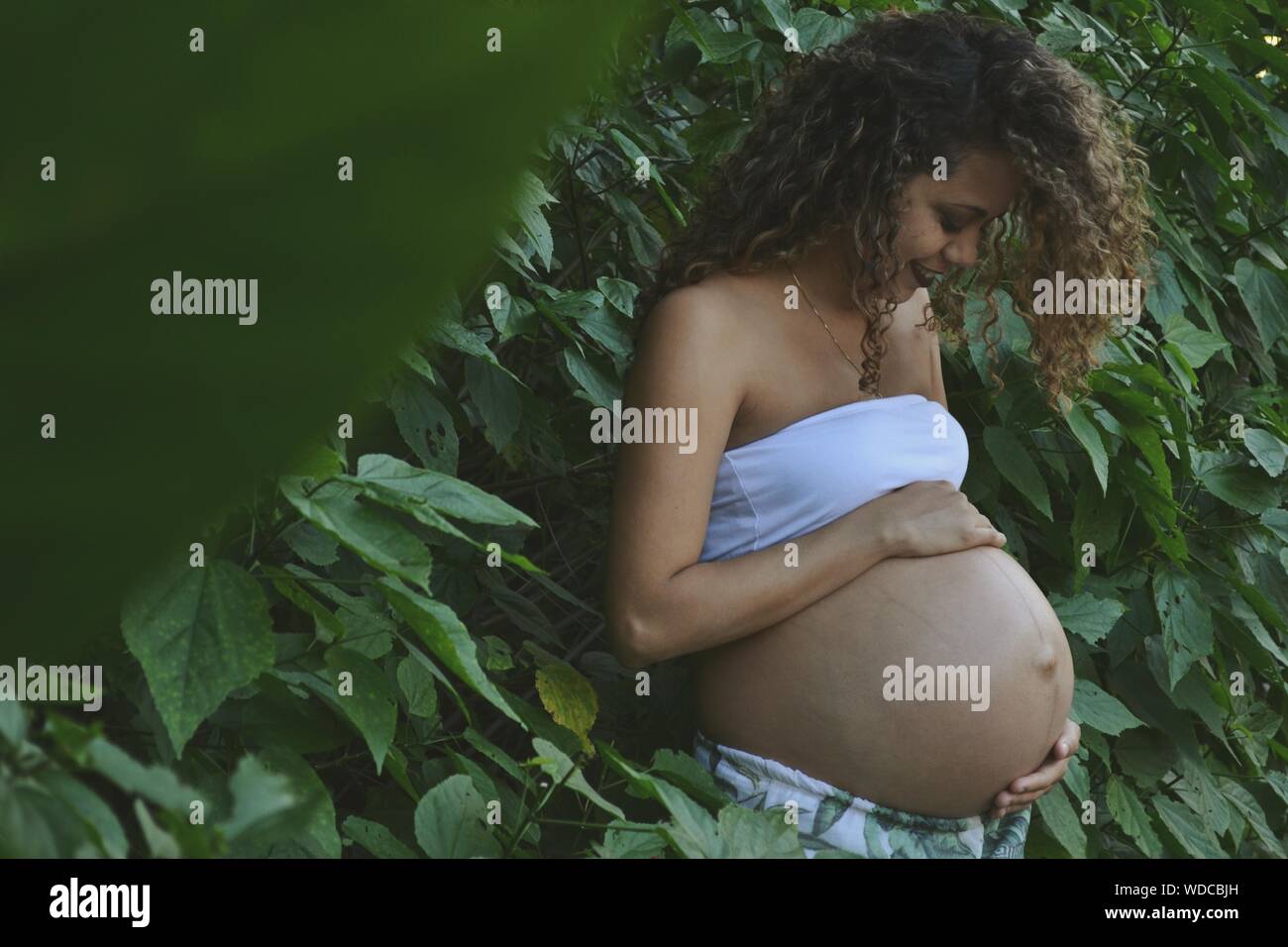 Pregnant Woman Standing By Plants Stock Photo