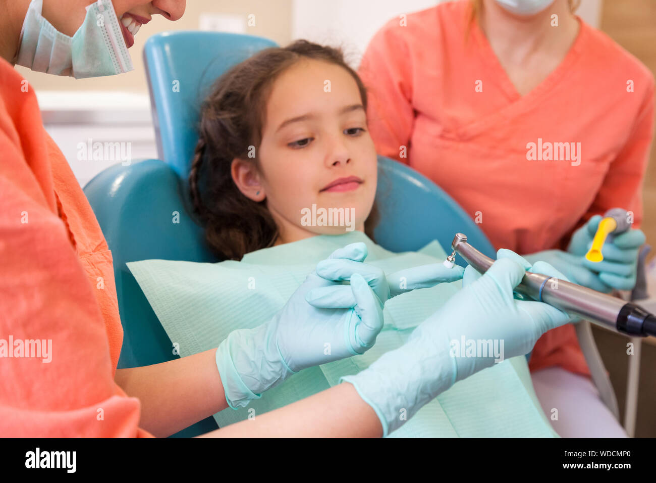 Pretty young girl a the dentist surgery for checkup with female dentist and assistant. Dentist showing dentist tool, close-up Stock Photo