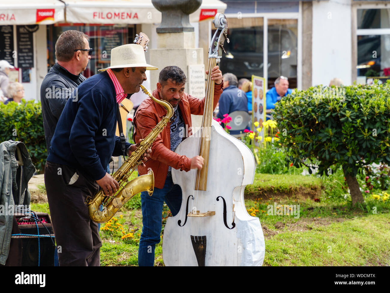 TAVIRA, PORTUGAL - MARCH 23, 2018: Three street musicians playing their instruments at Jardim da Alagoa park to entertain tourists (landscape orientat Stock Photo