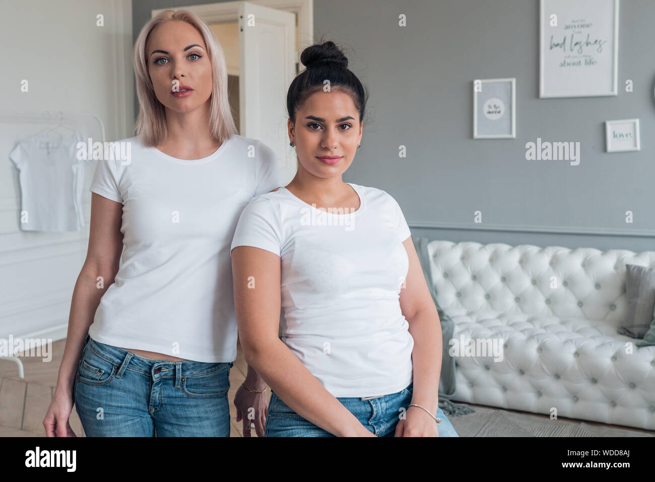 Portrait of two girlfriends blonde and brunette in white t-shirts without design Stock Photo