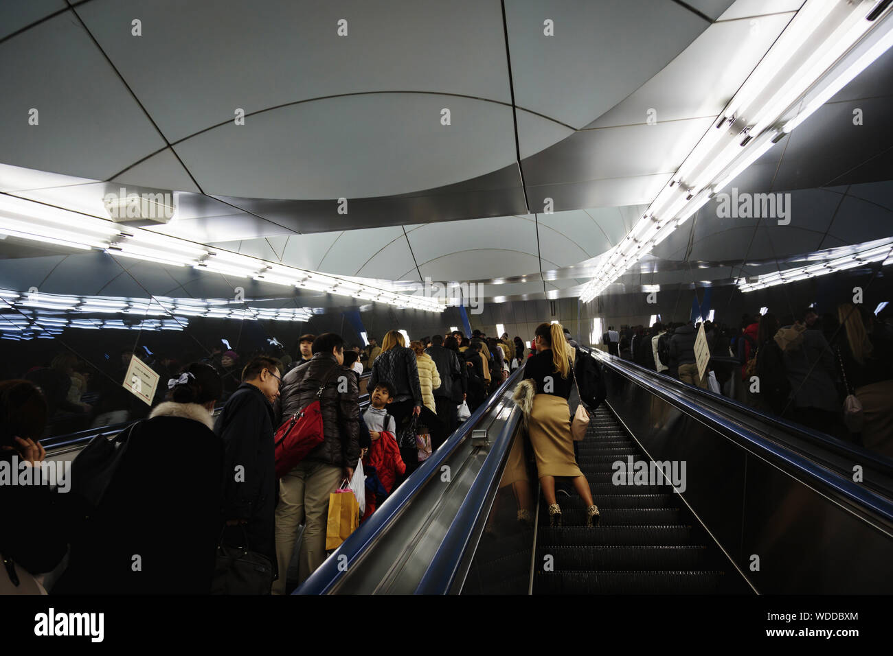 People traveling with escalators inside Shinjuku Station, a major railway station in the People traveling with escalators inside Shinjuku Station, a major railway station in the