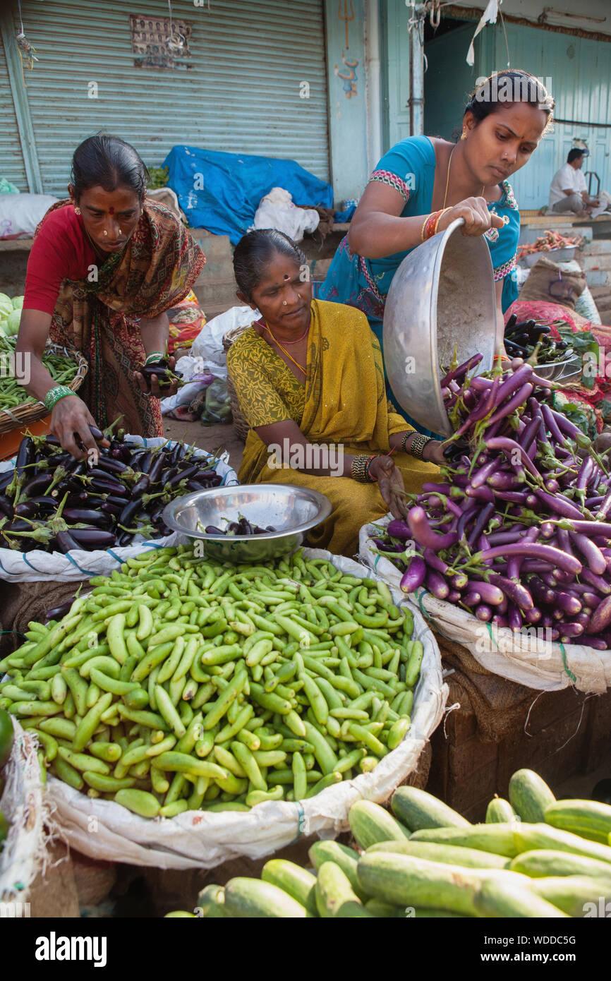 India, Telengana, Secunderabad, Vendor selling aubergines and cucumbers at the vegetable market in Secunderabad. Stock Photo