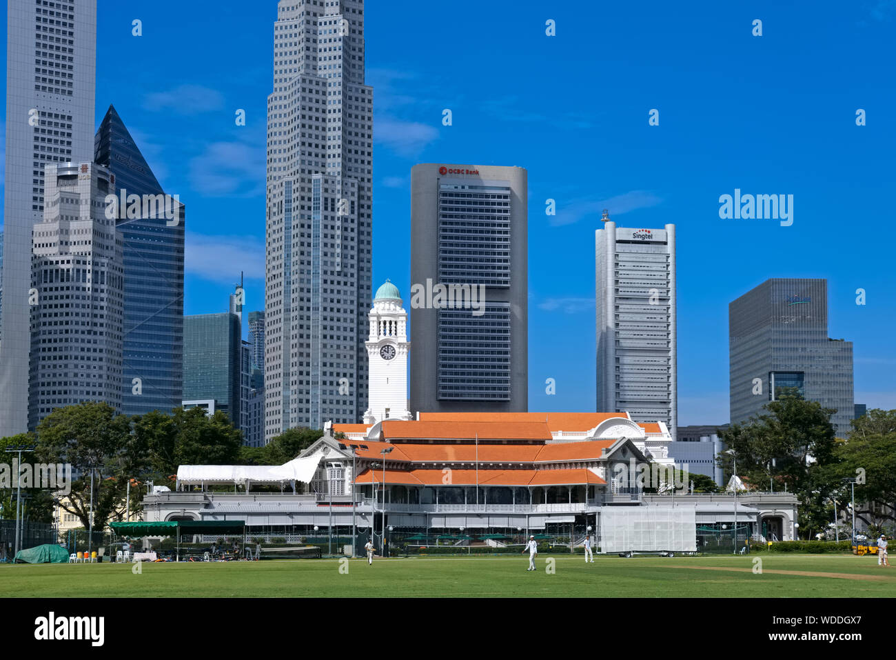 View across the Padang towards Singapore Cricket Club, Victoria Memorial Hall & Theatre with its clocktower and the banking district beyond; Singapore Stock Photo