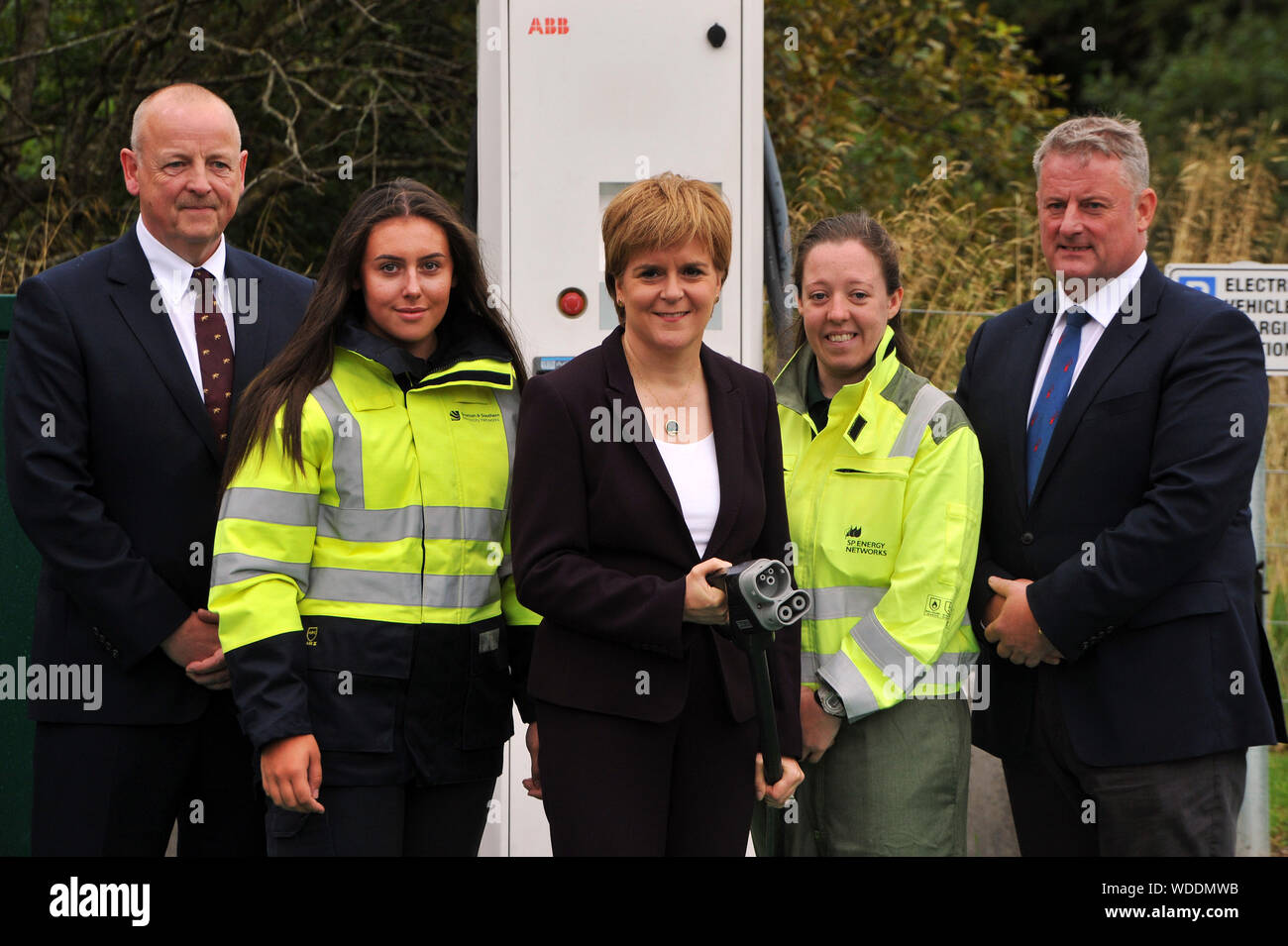 Scotland's First Minister Nicola Sturgeon holds an electric vehicle charging socket with SSE Networks Managing Director, Colin Nicol (left), SP Energy Networks (a unit of Scottish Power) CEO Frank Mitchell (right) and apprentices Darcie Lynch and Kirsten Gallagher during a visit to the University of Strathclyde's Power Networks Demonstration Centre in Cumbernauld, near Glasgow where she announced additional investment in the country's electric vehicle charging infrastructure. Stock Photo