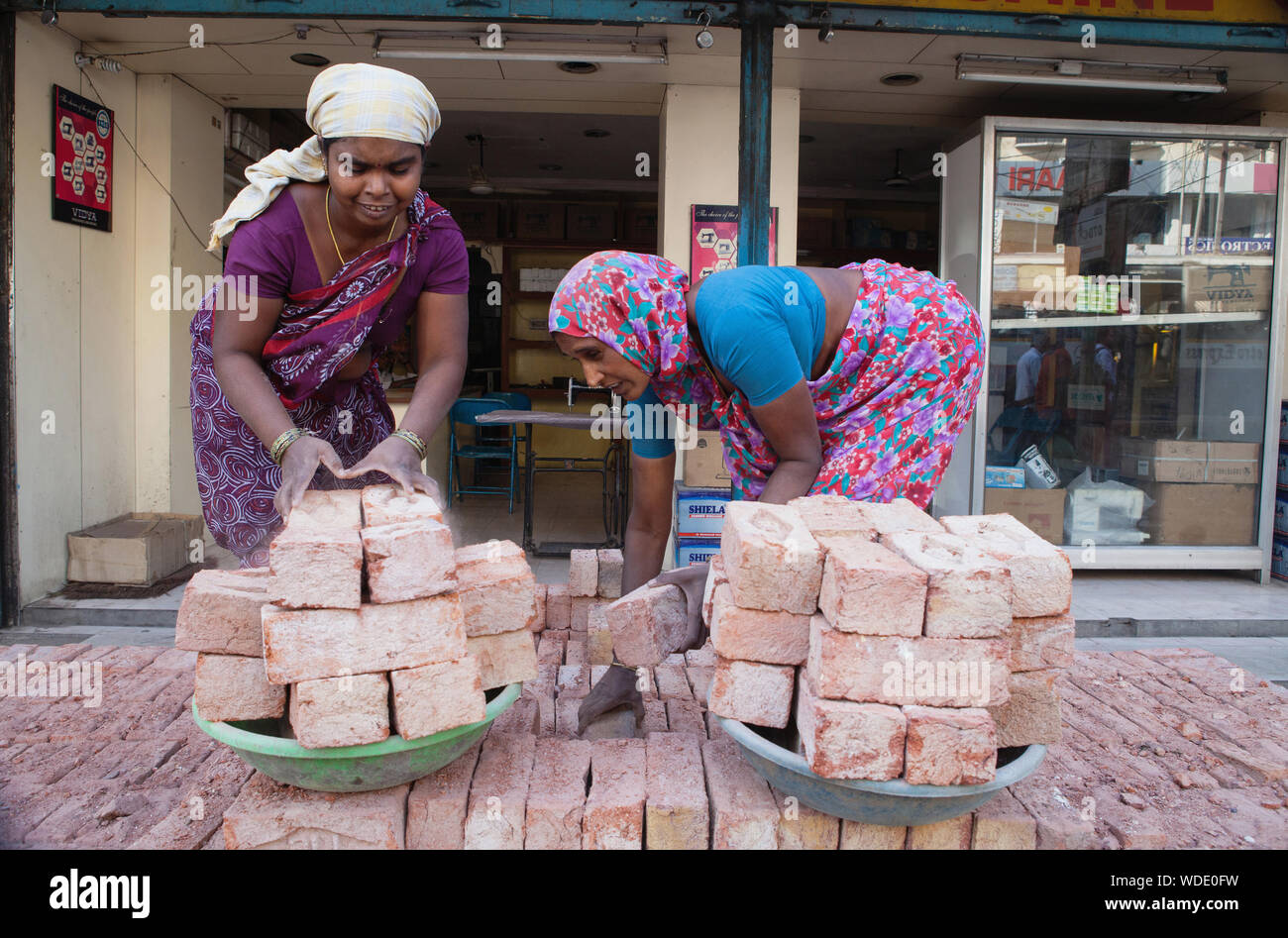 India, Telengana, Hyderabad, Female labourers loading bricks onto trays. Stock Photo