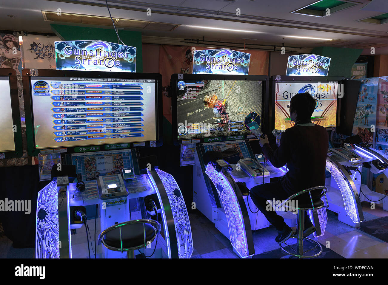 A man plays Gunslinger Stratos, a four-versus-four third-person shooter, inside Taito arcade store. Stock Photo