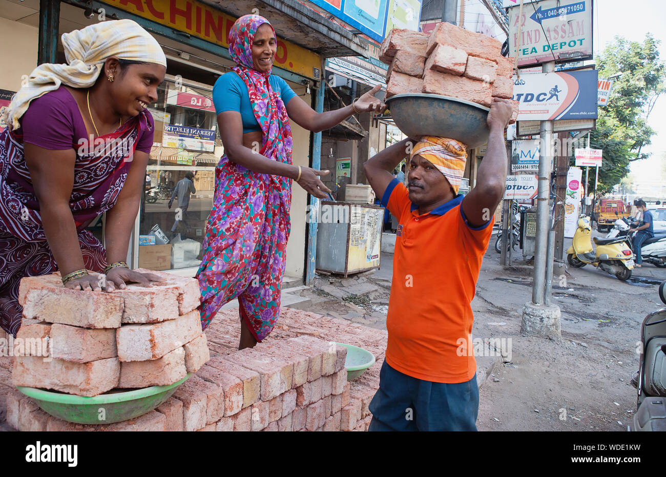 India, Telengana, Hyderabad, Labourers load bricks onto trays to carry on their heads. Stock Photo