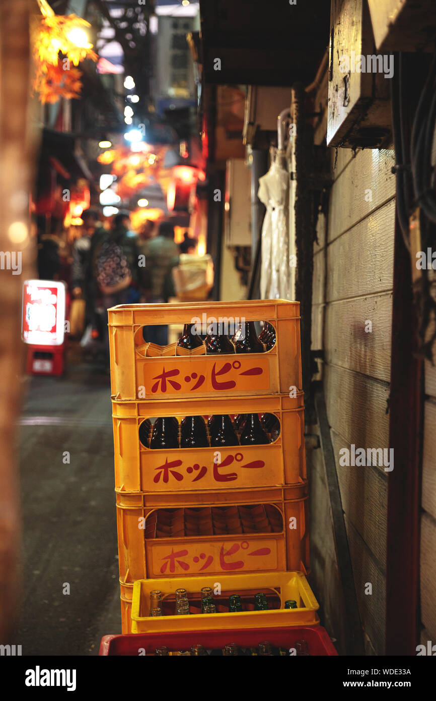 Stacked emptied bottles in yellow containers at Omoide Yokocho food alley near Shinjuku. Stock Photo