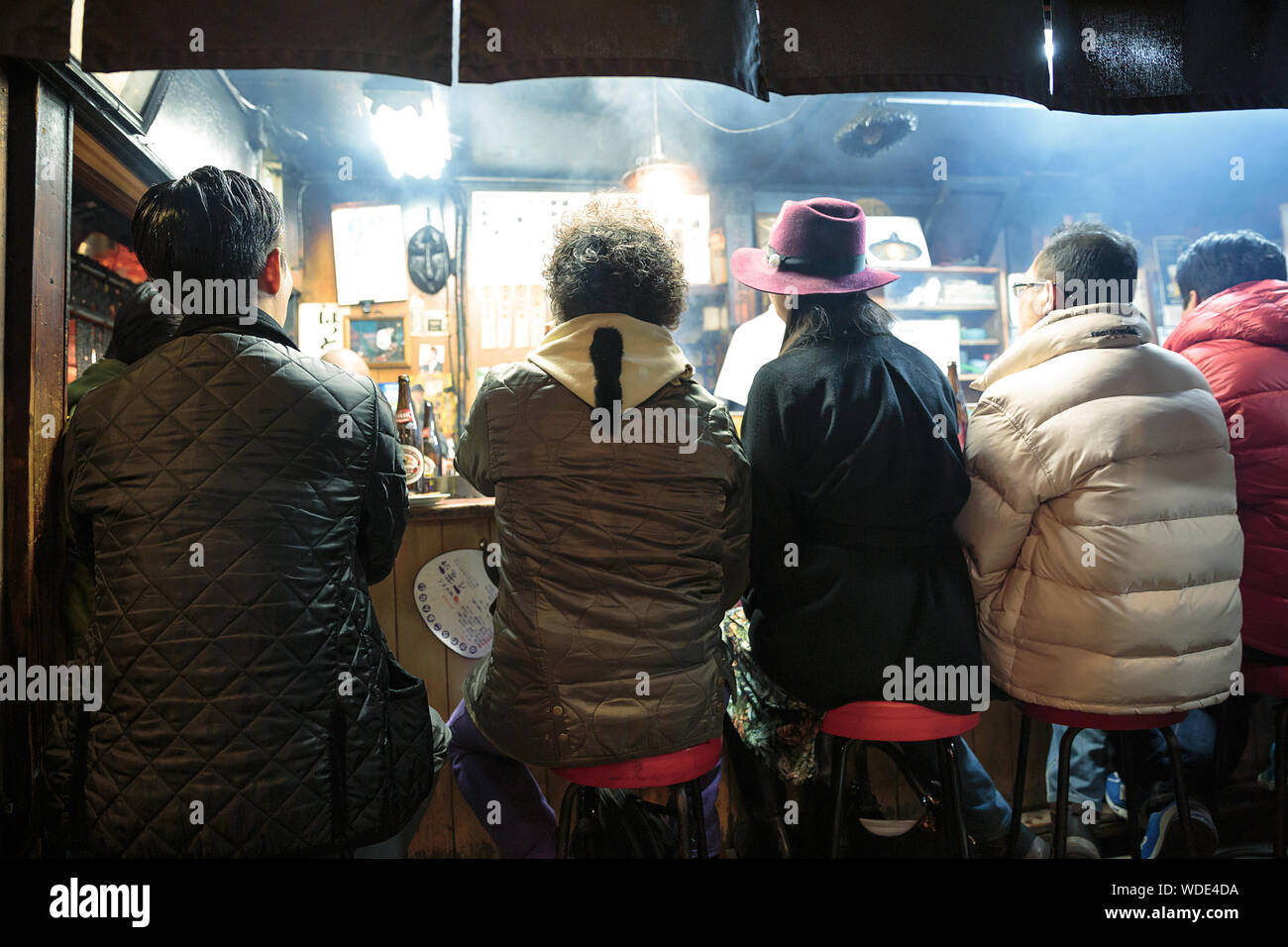 People enjoy drinks and street food inside a small pub in Omoide Yokocho alley. Stock Photo