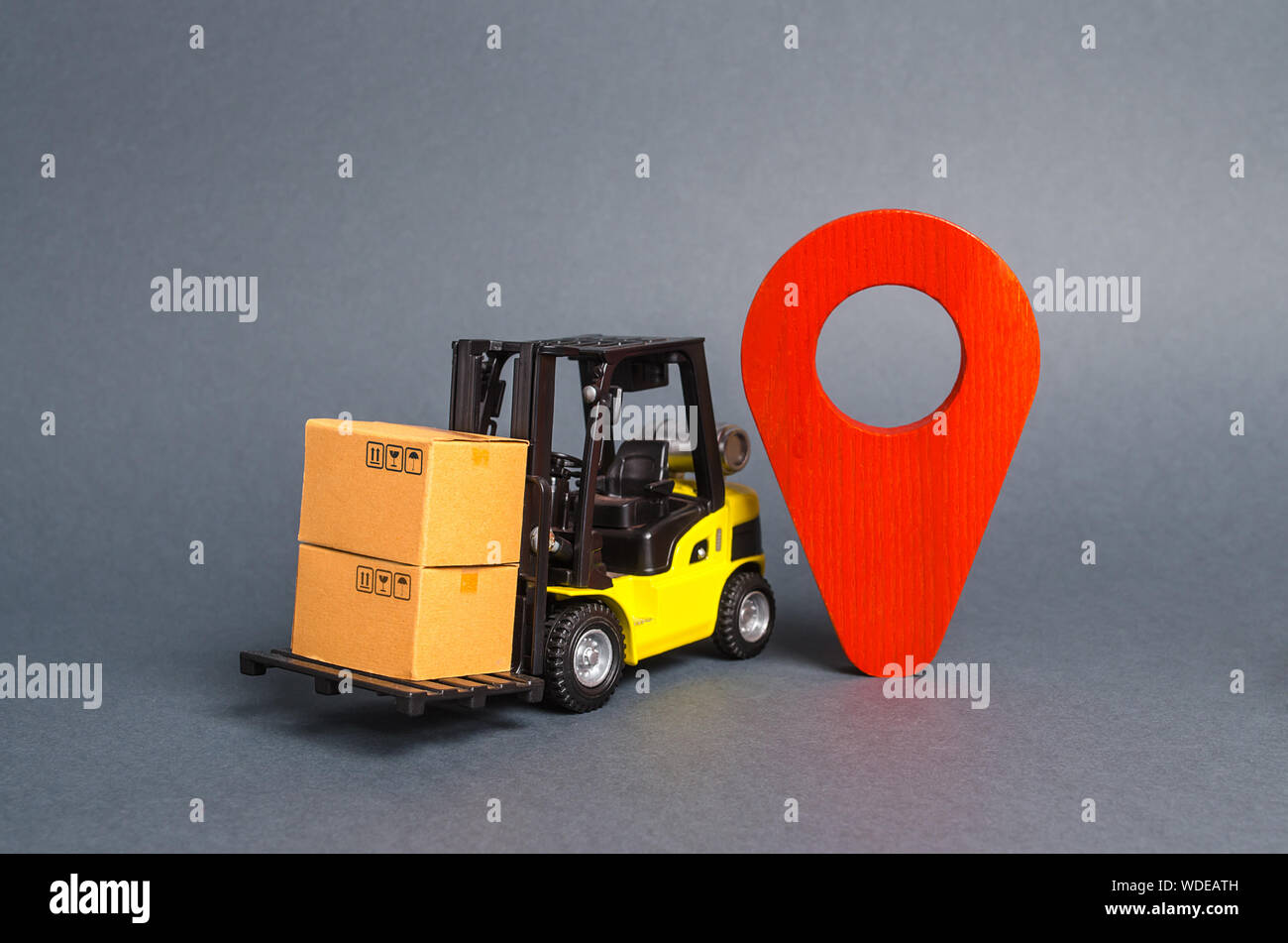 Yellow forklift carries boxes and a red location pointer ...