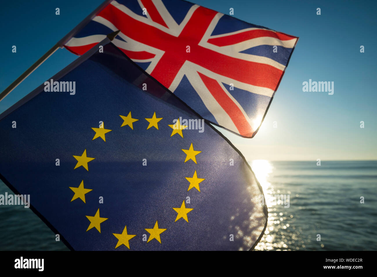 European Union and British Union Jack flags flying together as the sun rises on a new era on the relationship between the EU and the UK after Brexit Stock Photo