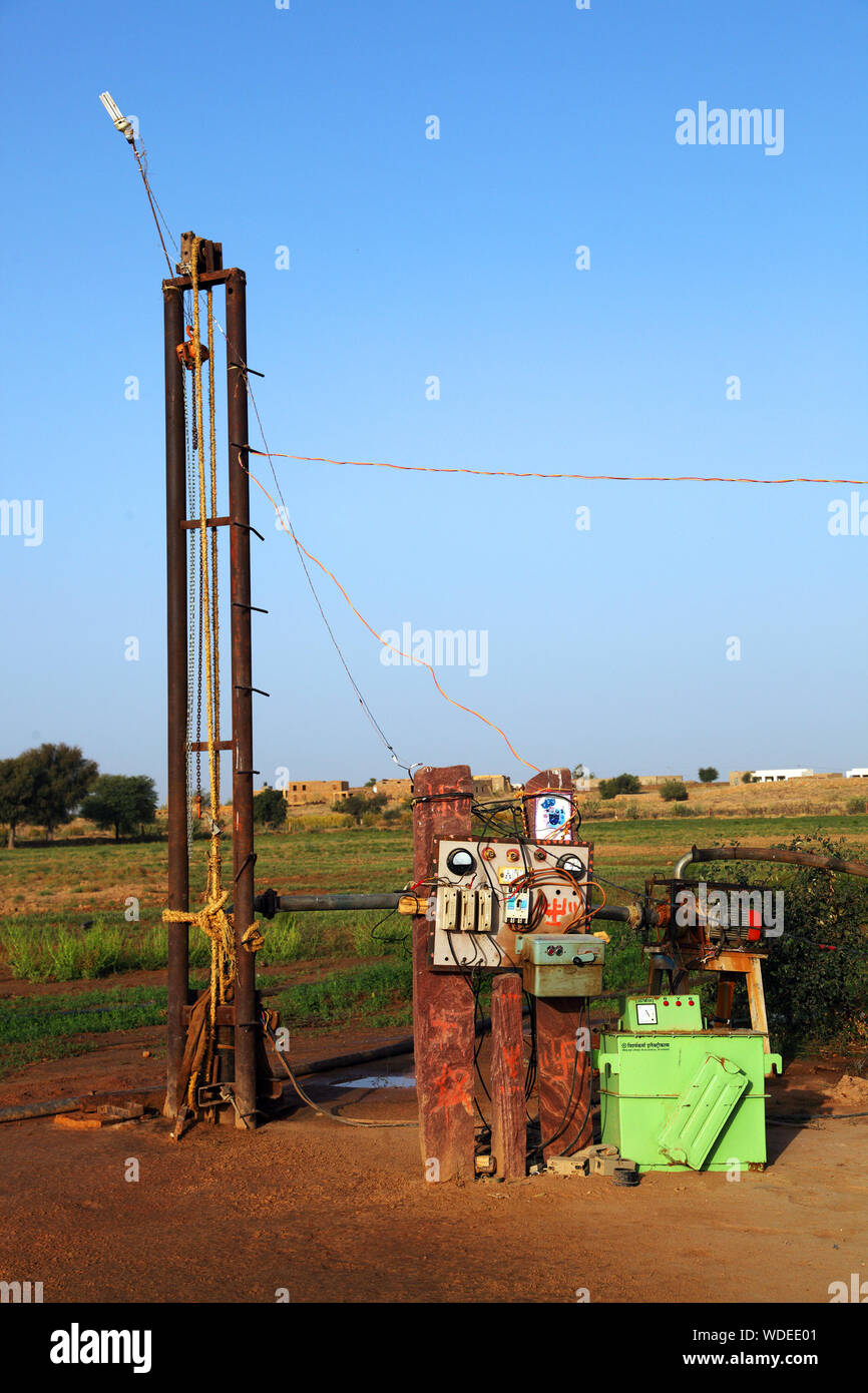 Water Drilling Machine By Grassy Field Against Clear Blue Sky Stock Photo