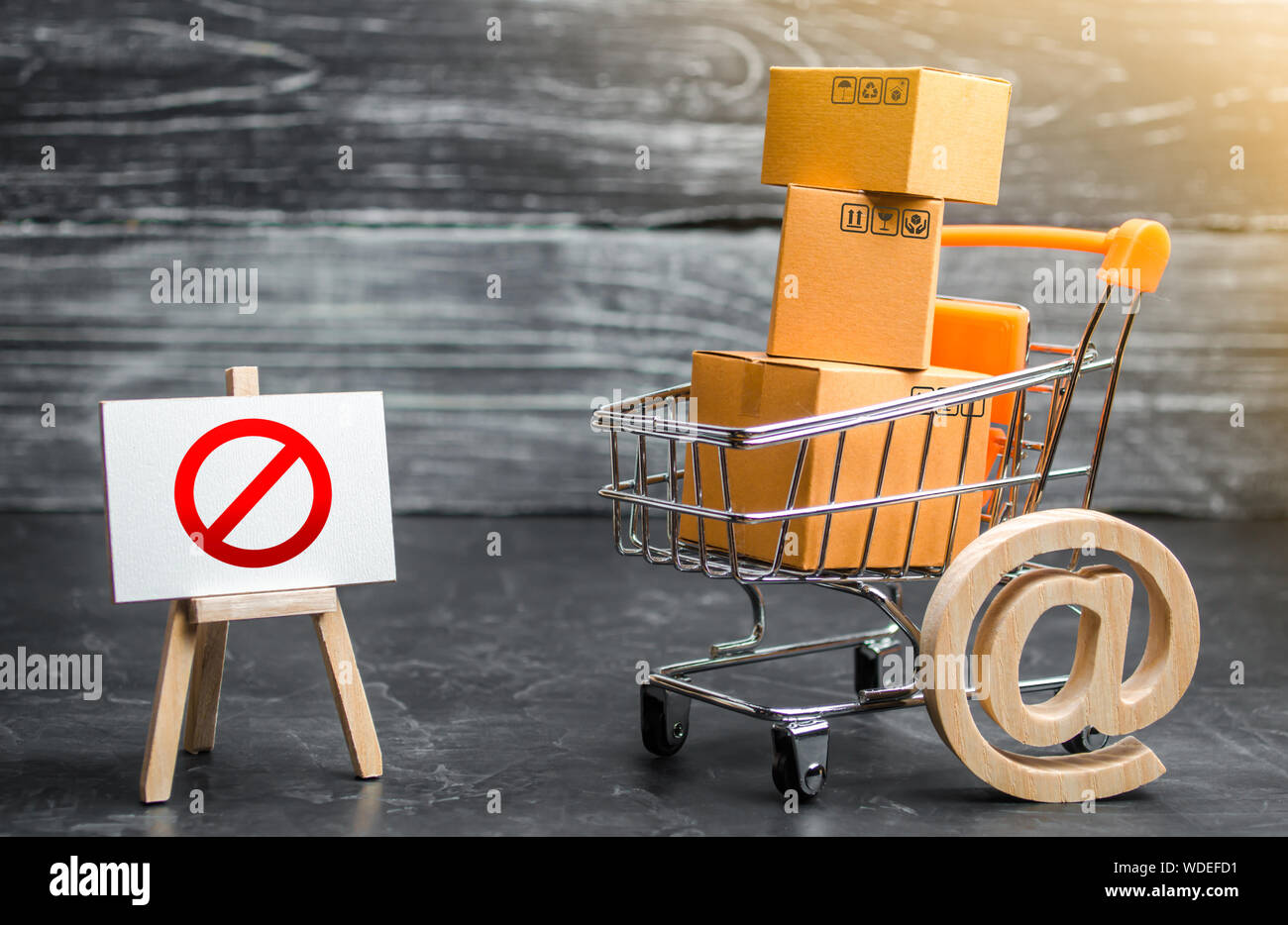 Trading cart with boxes and an easel with a prohibition symbol NO. Internet trade online shopping ban. Restriction on importation goods, proprietary f Stock Photo