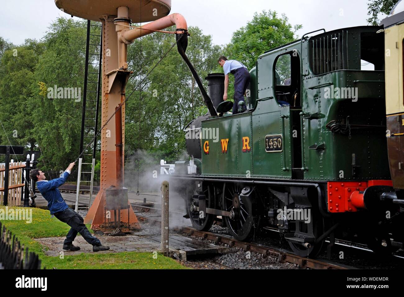 Young volunteer staff refill the water tanks of GWR 14XX class 1450 tank engine at Didcot Railway Centre, Oxfordshire Stock Photo
