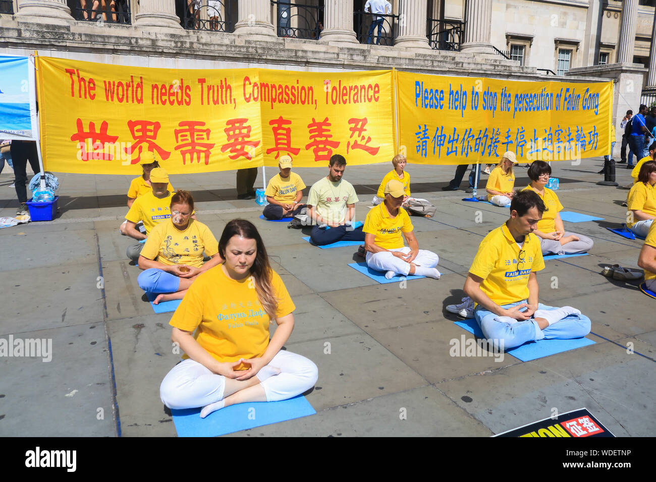 Members of the Falun Gong meditate in front of the National Gallery at the Trafalgar Square during the protest.Demonstration against their persecution in China. Falun Gong is Chinese religious spiritual practice that combines meditation and gong exercises with a moral philosophy cantered on the tenets of truthfulness, compassion, and forbearance. Stock Photo