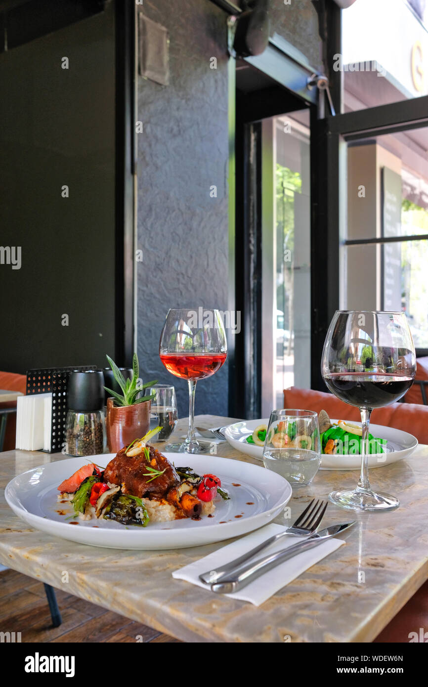 Pasta painted with organic paint, stuffed mussels, squid and lamb shank. Red and Rose Wine Stock Photo