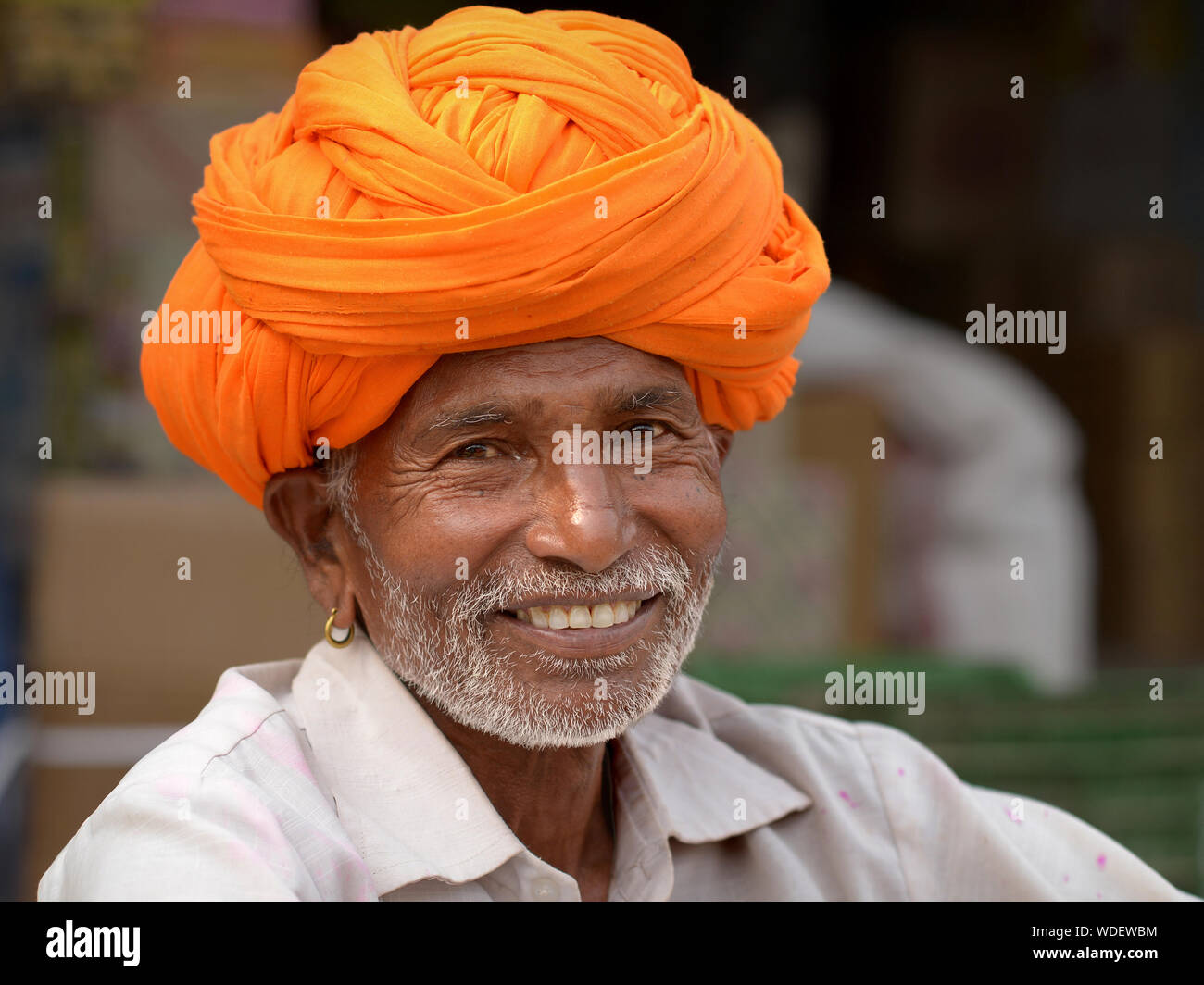 Indian Rajasthani man with orange turban smiles for the camera. Stock Photo