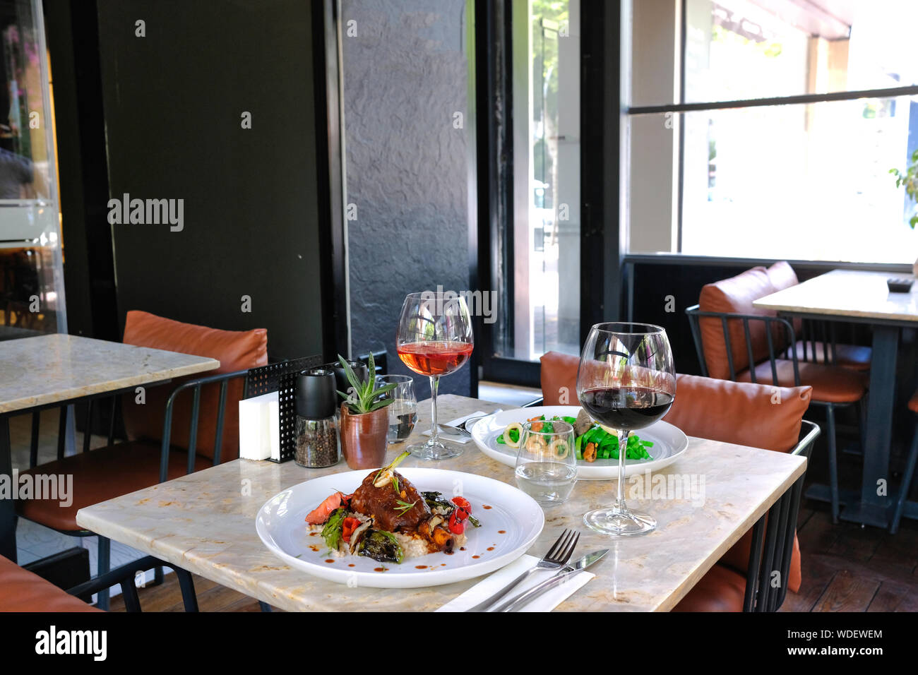 Pasta painted with organic paint, stuffed mussels, squid and lamb shank. Red and Rose Wine Stock Photo