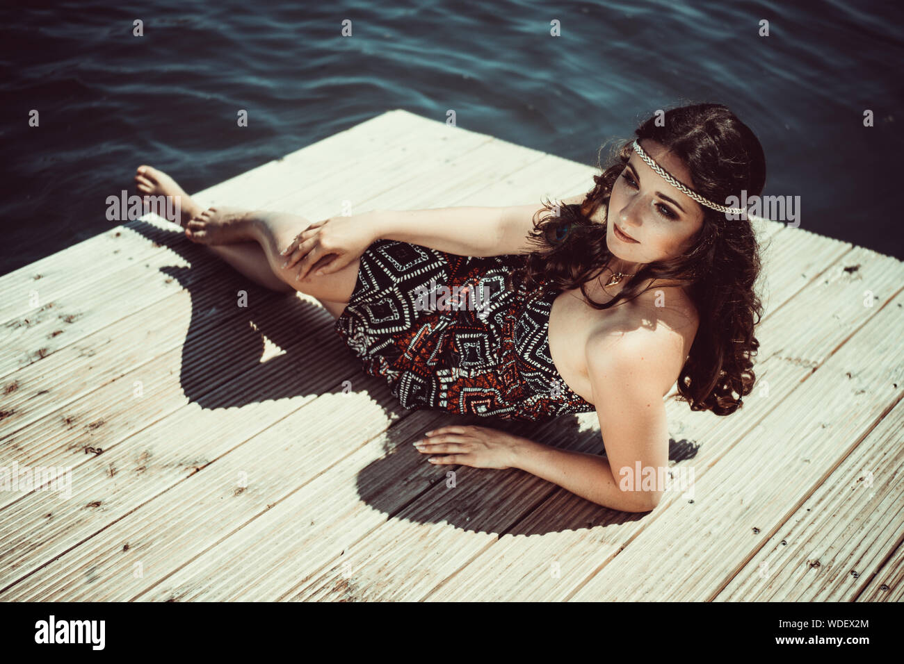Portrait Of Young Woman Lying On Pier Stock Photo