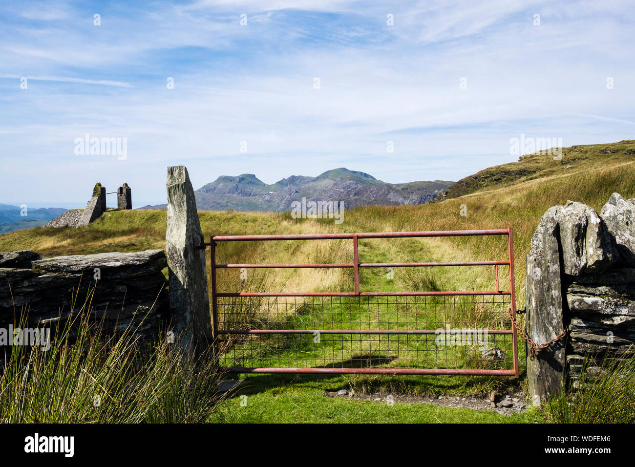 View to Moelwyns and metal farm gate in a dry stone wall on a country track through moorland in hills around Blaenau Ffestiniog, Gwynedd, Wales, UK Stock Photo