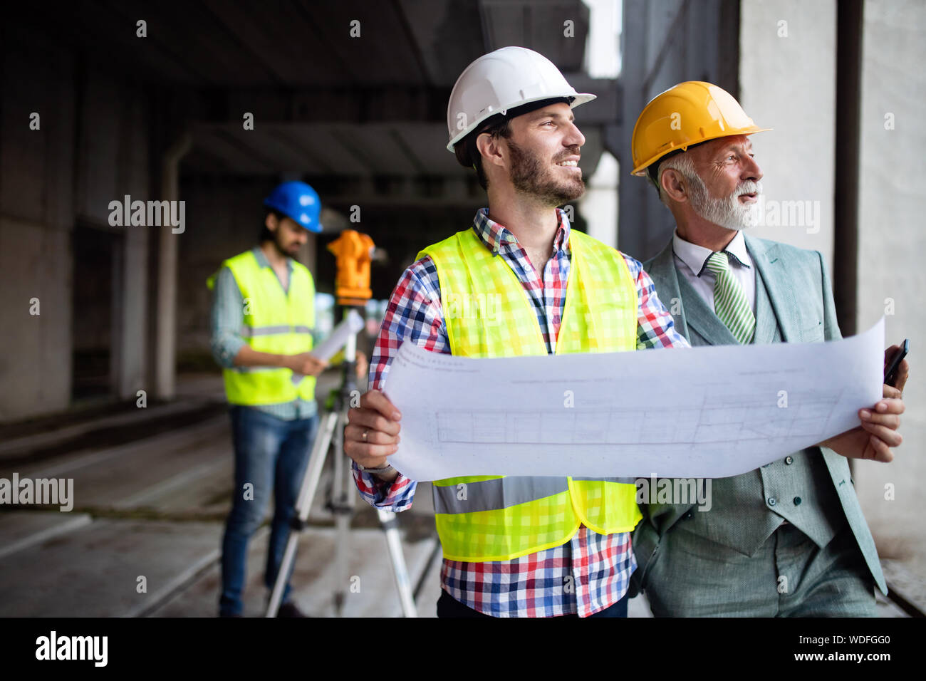 Engineer, foreman and worker discussing in building construction site Stock Photo