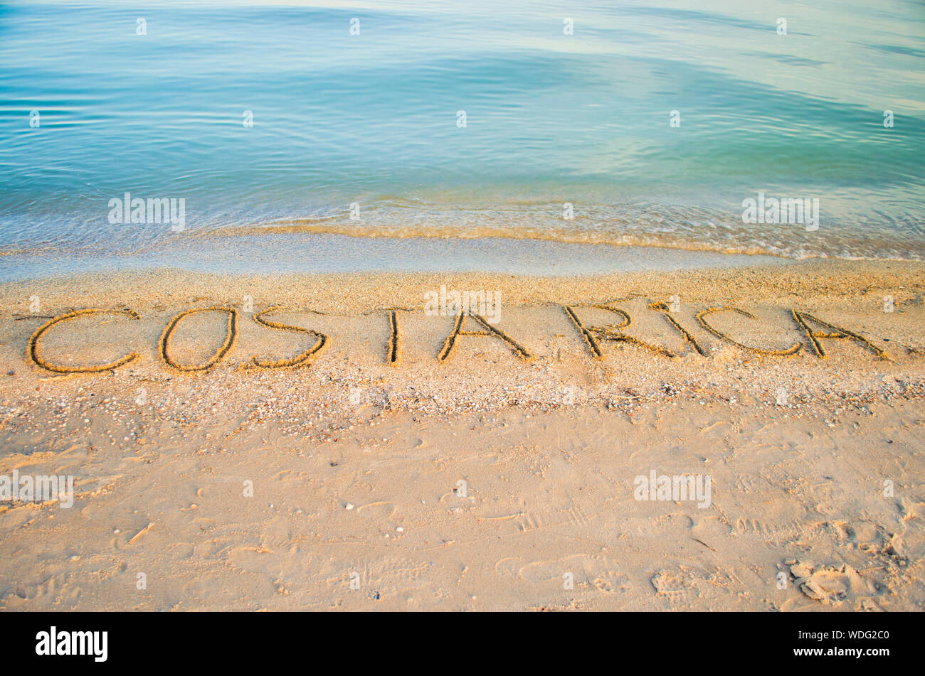 Costarica Text On Sea Shore Against Clear Sky Stock Photo