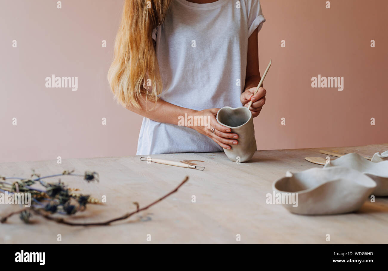 Unrecognizable woman working with clay mug standing at a table in studio Stock Photo