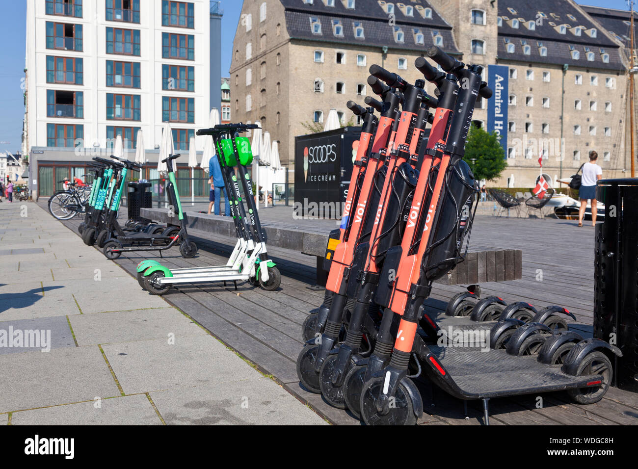 VOI, LIME and TIER rental e-scooters parked for hire at Larsens Plads in Copenhagen inner harbour. Stock Photo