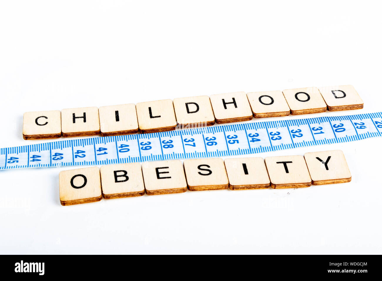 Health concept of a tape measure also showing the message Childhood Obesity Stock Photo