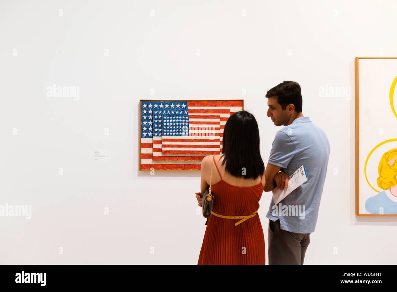 Whitney Museum, rear view of two young people in front of a painting by Jasper Johns (Three Flags), Whitney Museum Of American Art, New York City. Stock Photo