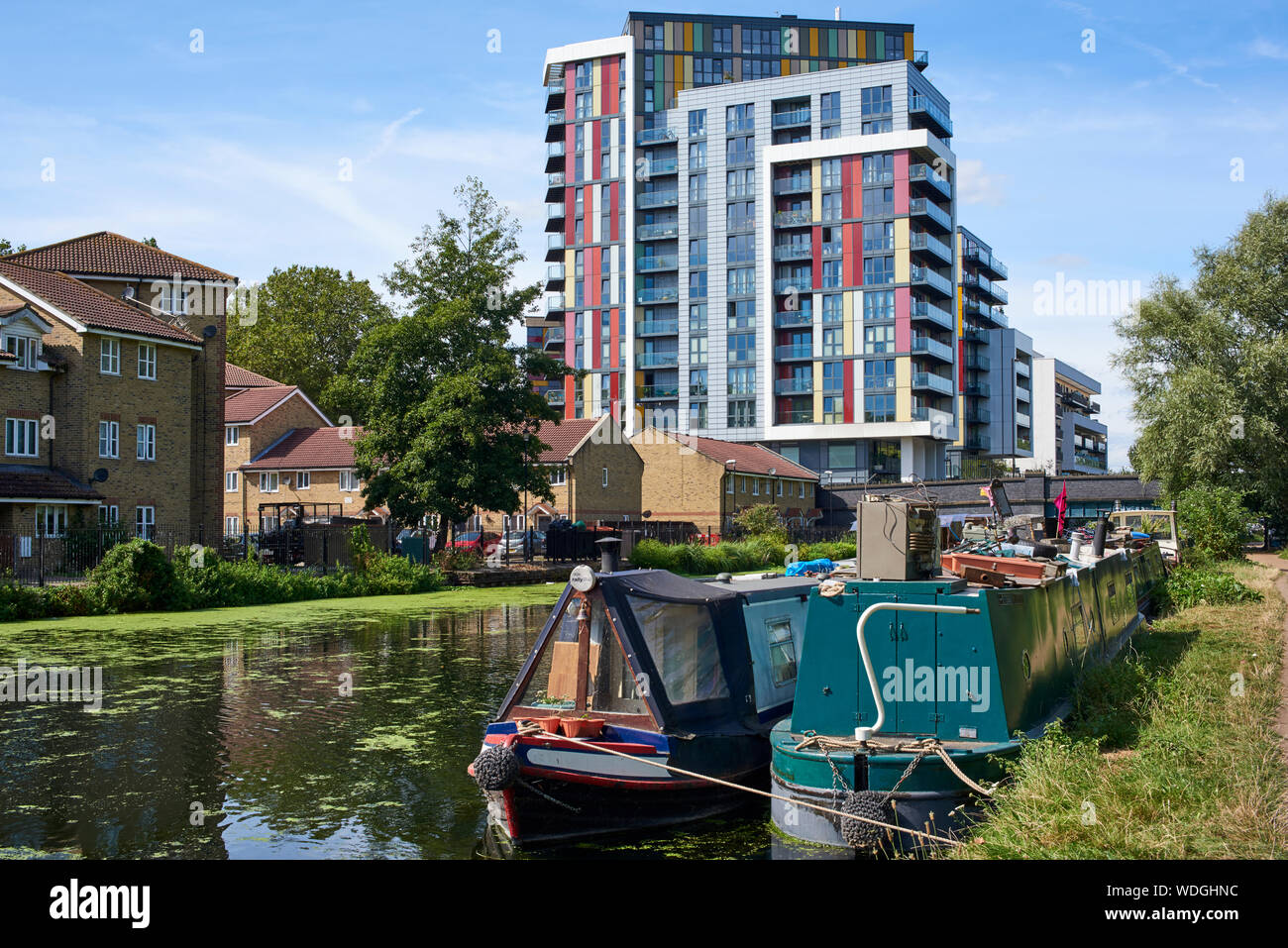Narrowboats moored on the River Lea Navigation at Hackney, London UK, with the new Matchmaker's Wharf apartments by the river Stock Photo