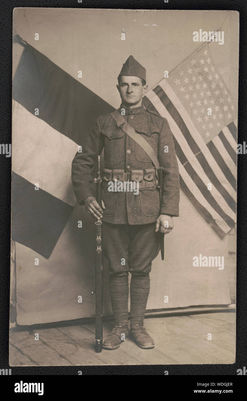 George Hasken in uniform with rifle in front of French and American flags Abstract/medium: 1 photograph : gelatin silver print  sheet 14 x 9 cm (postcard format) Stock Photo