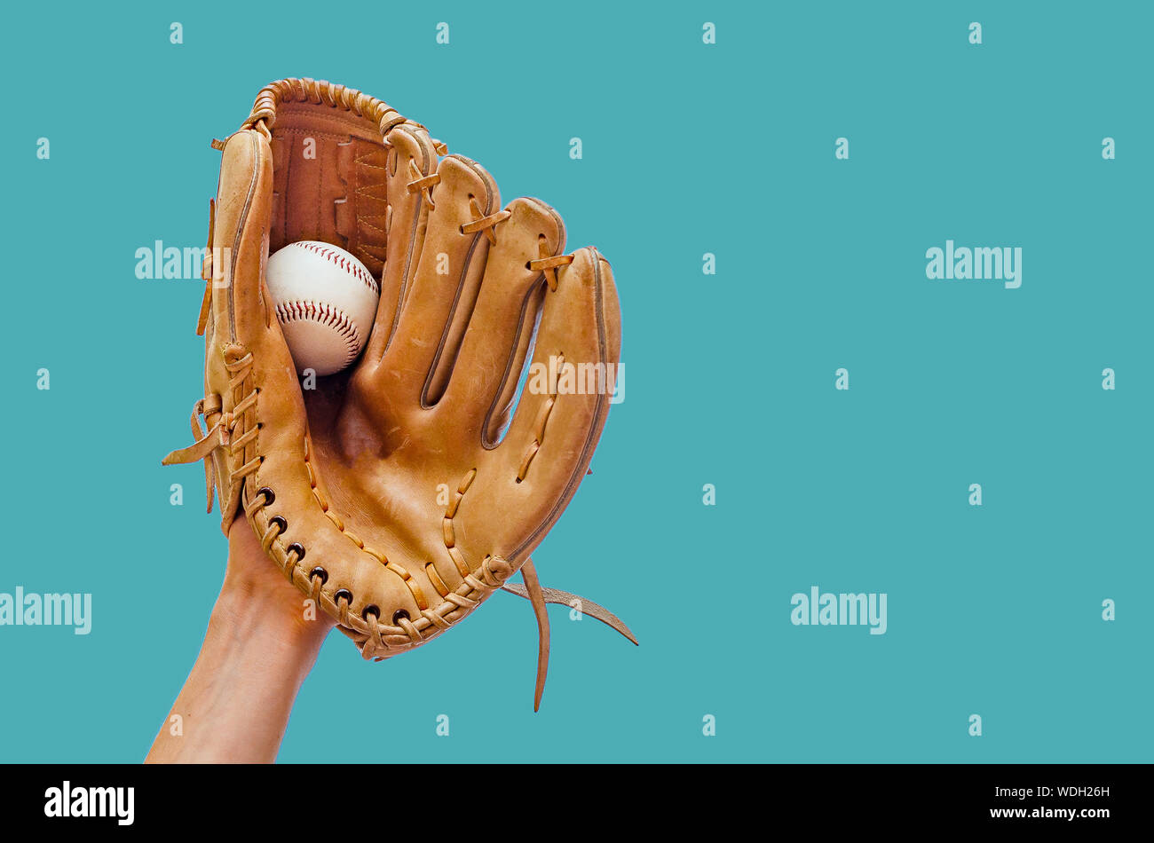 Hand in a leather baseball glove caught a ball on a green background