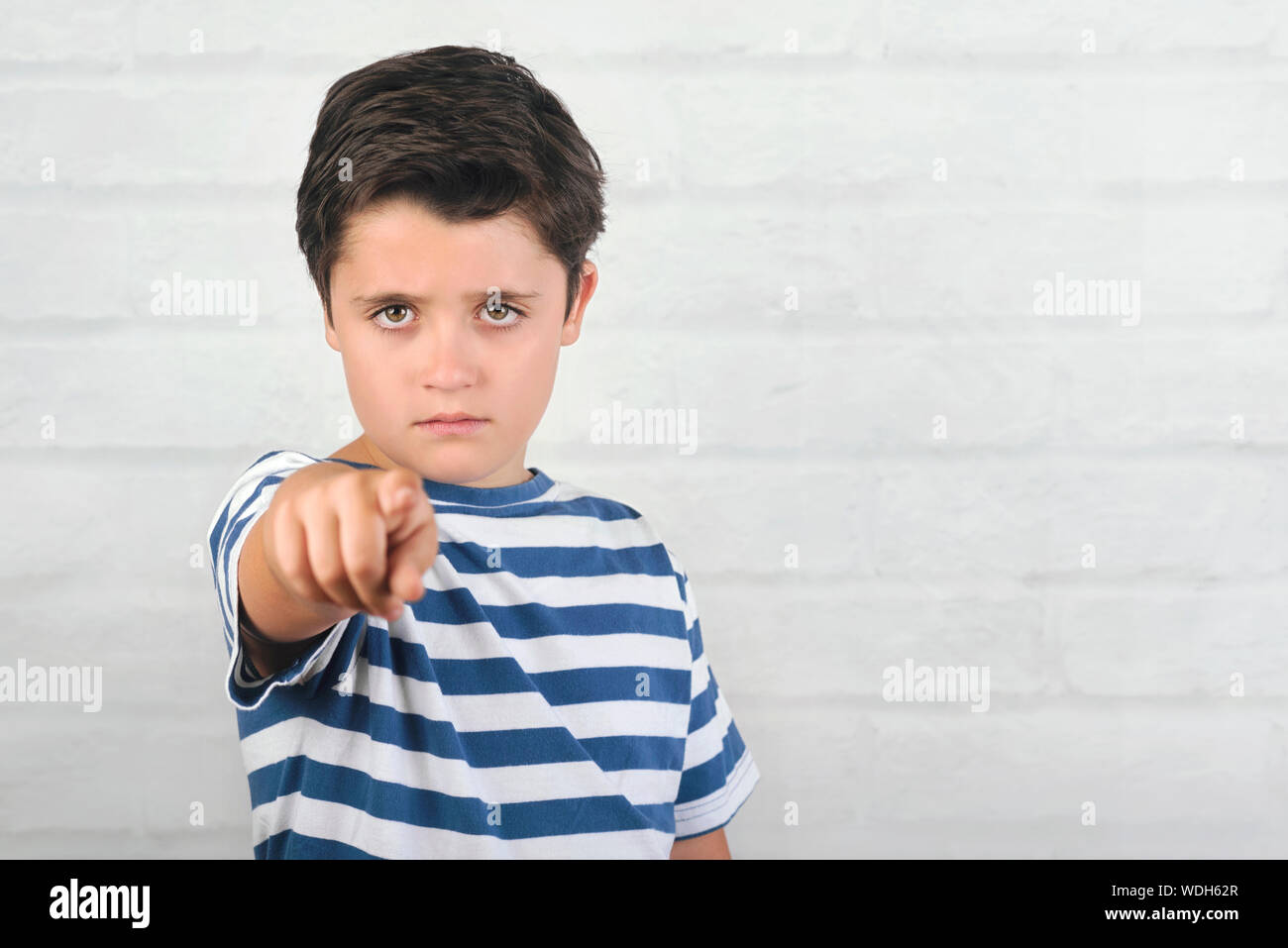angry child pointing front on brick background Stock Photo