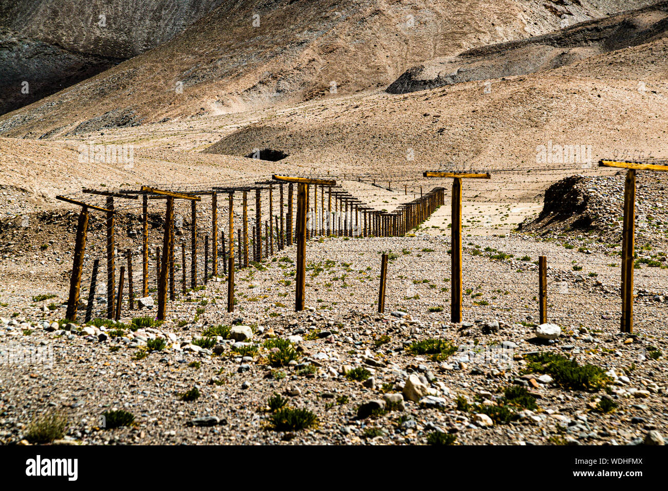 In the sparsely populated mountainous landscape along the Chinese border, a barbed wire fence stretches for hundreds of kilometers near Музкол, Tajikistan Stock Photo