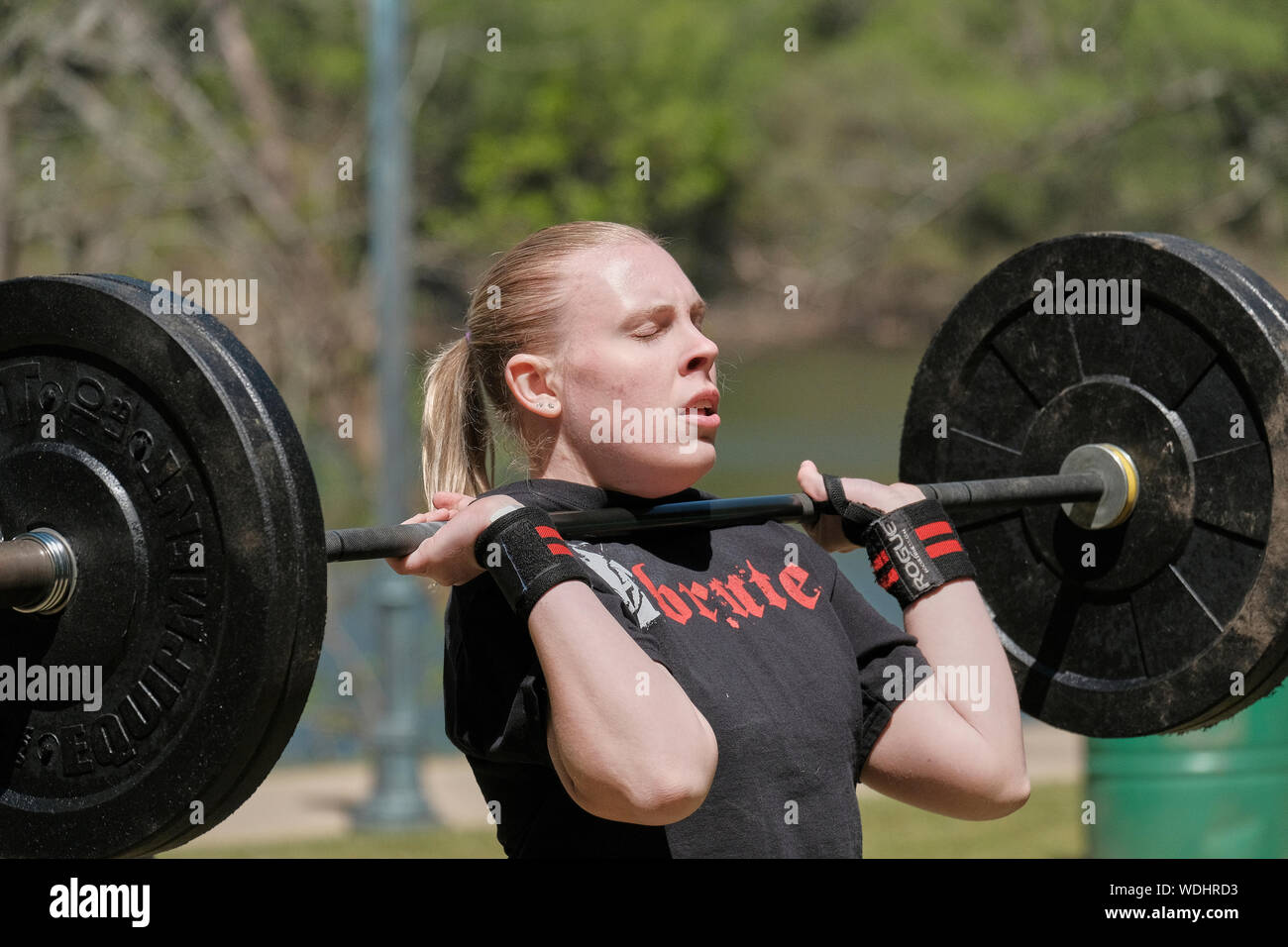 Female or woman competing in a CrossFit fitness challenge competition by dead lifting weights or weightlifting. Stock Photo