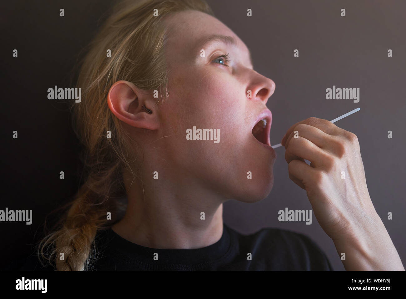 Woman doing DNA test with cotton swab at home. Test for home use Stock