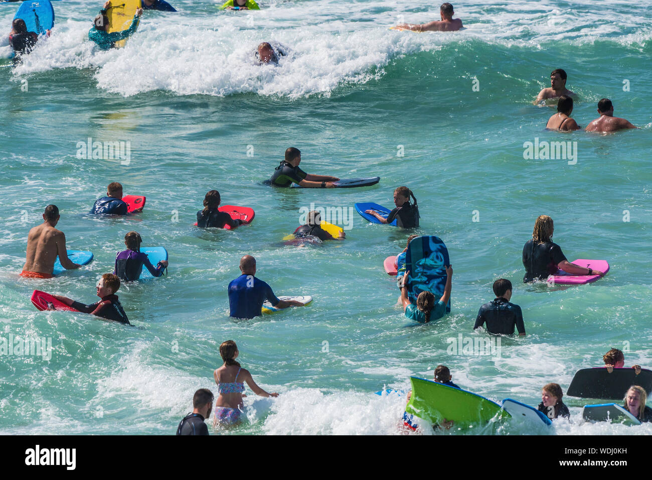 Holidaymakers on a staycation holiday enjoying themselves in the sea at Fistral in Newquay in Cornwall. Stock Photo